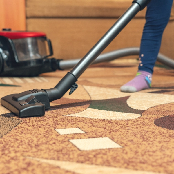 A small child vacuums a carpet with a vacuum cleaner